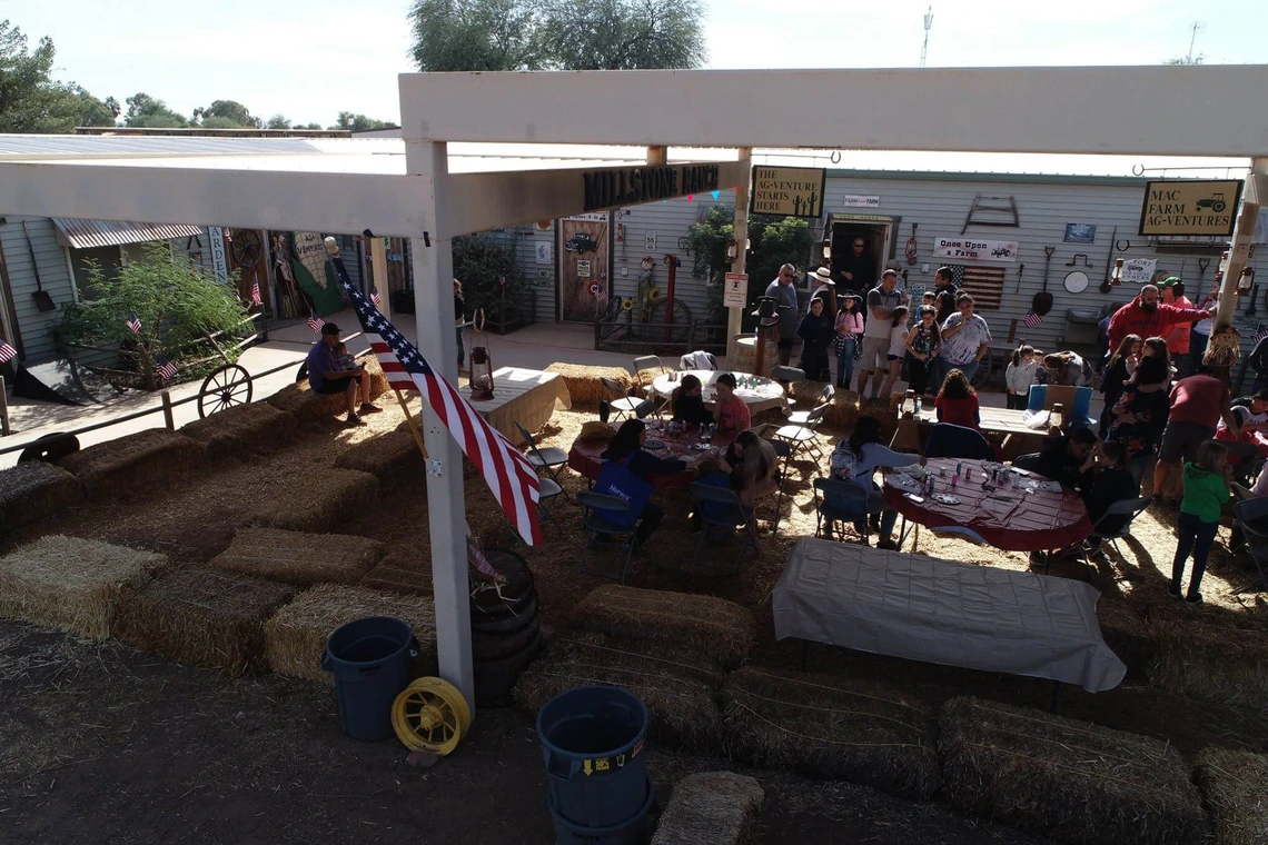 families with young children around tables under pavilion with hay on floor
