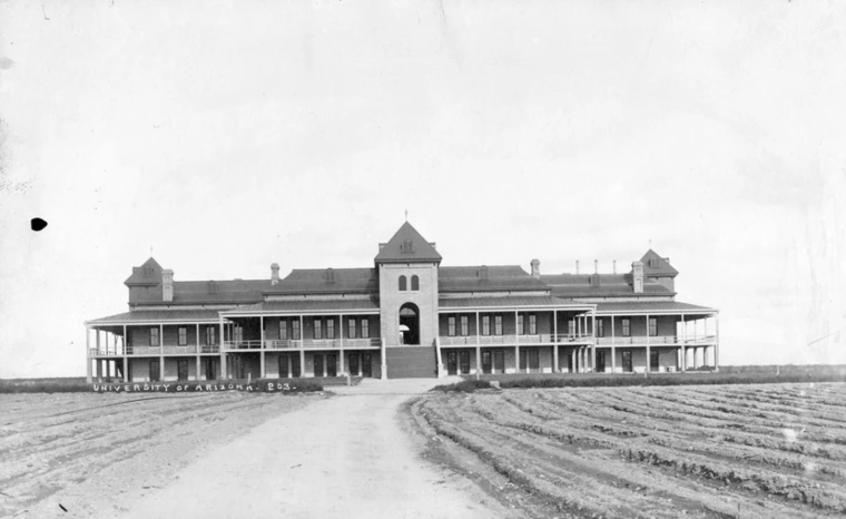 A historic image of old main, showing tilled fields in the foreground